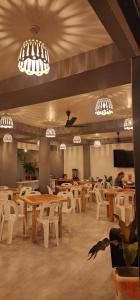 un restaurante con mesas, sillas blancas y lámparas de araña en Rihiveli Residence Thoddoo, en Thoddoo