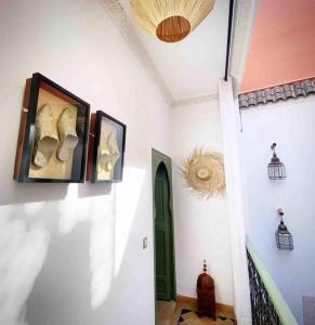 einen Flur mit grüner Tür und Bildern an der Wand in der Unterkunft Riad ABADA Medina Marrakech (Sidi Mimoun) in Marrakesch