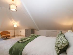a bedroom with a white bed with a green blanket at Apartment 16 in Y Felinheli