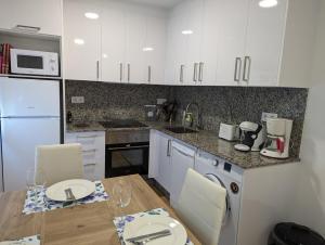a kitchen with white cabinets and a table with chairs at Casa hierro in Vigo