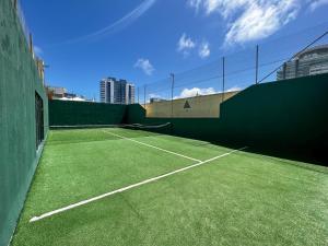 una pista de tenis con césped verde al lado en Apartamento Torre Triangulo Mansa, en Punta del Este