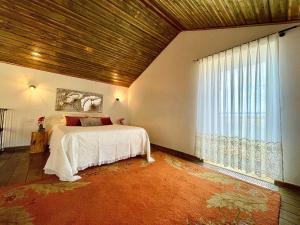 a bedroom with a bed and a large window at Tufa Guest House, Wellness & SPA - Villa Campus in Corredoura