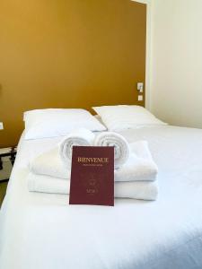 - un lit avec des serviettes blanches et un panneau sur celui-ci dans l'établissement Hôtel Némo Aéroport de Pau - KB HOTEL GROUP, à Sauvagnon