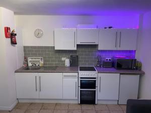 een kleine keuken met witte kasten en een paars plafond bij Deluxe Seaside Ground Floor Apartment With Patio & Private Entrance, marine court in Bundoran