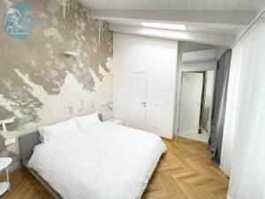 1 dormitorio con cama blanca y pared en Tarabochia 8 Tirabora Short Rent, en Trieste