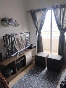 モンガグァーにあるEdifício Maison badezirのテレビと大きな窓のあるリビングルーム