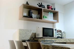 a kitchen with a counter with a microwave and chairs at Imperial Flat Tambaú 311 in João Pessoa