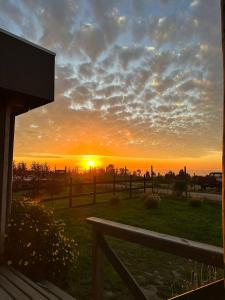 un coucher de soleil sur un champ avec une clôture en bois dans l'établissement 7 Olas lodge, à Algarrobo