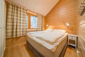 a small bedroom with a bed in a wooden room at Levillas Lammaskuru in Levi