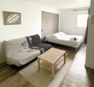 - un salon avec un canapé et un lit dans l'établissement Hôtel Némo Aéroport de Pau - KB HOTEL GROUP, à Sauvagnon