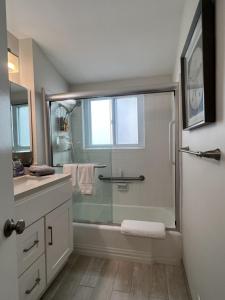 baño con bañera y ducha con ventana en Heart of Corona Del Mar 2 Bed 2 bath gem HUGE Patio and Front yard en Newport Beach