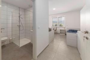 ein weißes Bad mit einer Dusche und einem Waschbecken in der Unterkunft RM Roma Studio in Celje