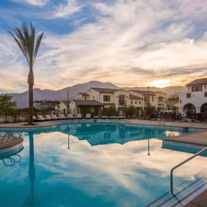 a pool at a resort with a palm tree and buildings at BRAND NEW La Quinta Home in Signature at PGA West in La Quinta