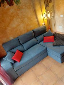 um sofá azul com almofadas vermelhas num quarto em El Ático de Mijares em Mijares