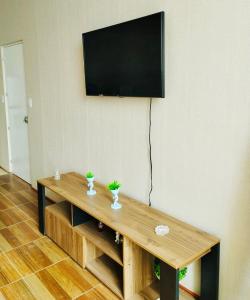einen Holztisch mit einem TV an der Wand in der Unterkunft 3J's House in Tarapoto
