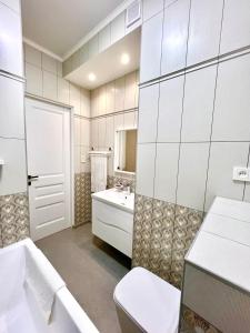 uma casa de banho com uma banheira, um WC e um lavatório. em Элитная квартира возле площади em Shymkent