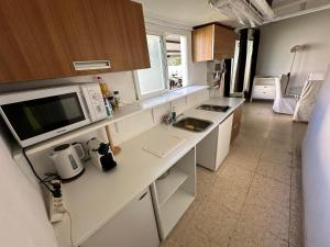 a kitchen with a counter with a microwave and a sink at apartamento acogedor con piscina y chimenea in Nuevo Baztán
