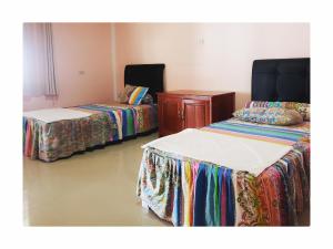 a room with two beds and a dresser in it at Raffiel Nias in Lagudri