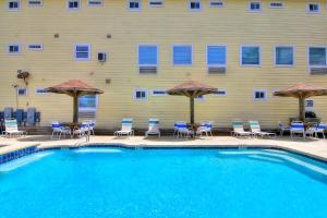 a swimming pool with chairs and umbrellas in front of a building at Beachgate Condo Suites and Hotel 512a condo in Port Aransas
