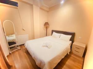 MG Apartments in Tbilisi في تبليسي: غرفة نوم صغيرة بها سرير أبيض ومصباح