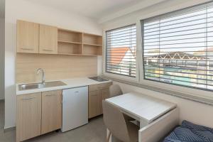 eine Küche mit einem Waschbecken, einem Tisch und einem Fenster in der Unterkunft RM Roma Studio in Celje