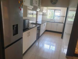uma grande cozinha com armários e electrodomésticos brancos em Bianca's em Matola