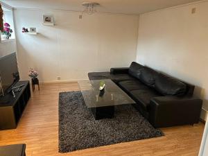 a living room with a black leather couch and a table at A Cozy Place To Stay Over in Tysvær