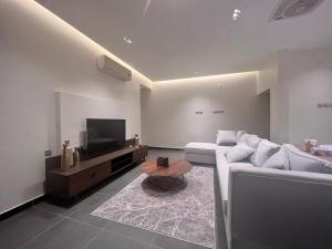 ein Wohnzimmer mit einem weißen Sofa und einem TV in der Unterkunft Wadishab balcony in Ash Shāb