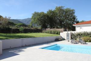 einen Pool mit zwei Stühlen neben einem Haus in der Unterkunft Modern 4 bedroom villa, air-conditioning, swimming pool, private gardens in Laroque-des-Albères
