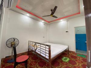 a bedroom with a bed with a ceiling fan and a chair at Tapama Resort Bakkhali in Bakkhali