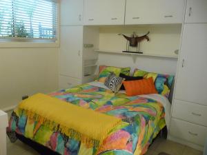 1 dormitorio con 1 cama con un edredón colorido en Orchard Garden, en Old Reynella