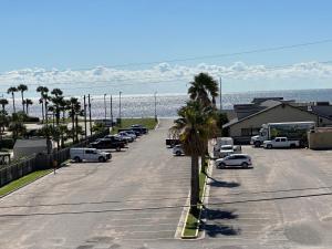 a parking lot with cars parked next to the ocean at Baymont by Wyndham Galveston in Galveston