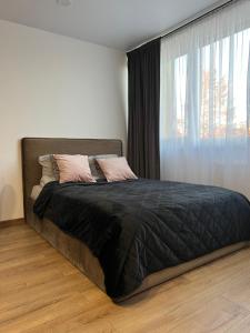 a bed in a bedroom with a large window at 111 Studio Apartment near Old town in Klaipėda