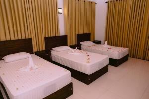 three beds in a room with curtains at Yala Wild Hut - Backpackers Lodge in Tissamaharama