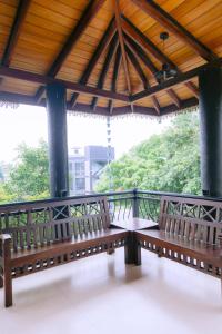 two benches sitting on a porch with a roof at Yala Wild Hut - Backpackers Lodge in Tissamaharama