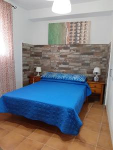 a bedroom with a blue bed and a brick wall at Torre de Guzmán, a un minuto andando de la playa, en el mejor sitio de Conil in Conil de la Frontera