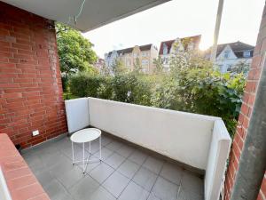 un taburete blanco sentado en un balcón con una pared de ladrillo en Work&Stay Apartment - Kiel en Kiel