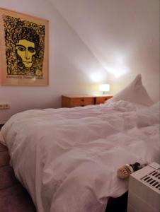 a bedroom with a white bed with a picture on the wall at Spacious & comfortable guestrooms w private bathrooms near Koelnmesse & Lanxess Arena, free parking, highspeed WiFi in Cologne
