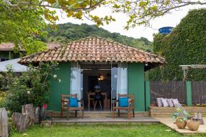 una pequeña casa verde con mesa y sillas en Pé na areia, tranquilidade,conforto,2 quartos, ar-cond, Wi-Fi, pet-friendly, 7 pessoas,, en Bombinhas