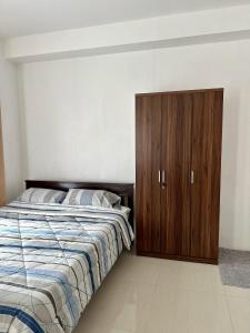 um quarto com uma cama e um armário de madeira em Modena TownSquare in Minglanilla em Minglanilla