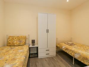 a bedroom with two beds and a white cabinet at Rabbits Warren in Lydney