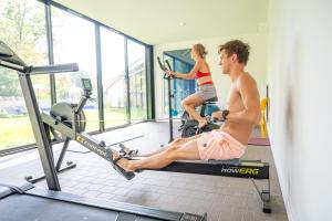 a man and a woman on a treadmill in a gym at Hôtel Lac d'Orient in Mesnil-Saint-Père