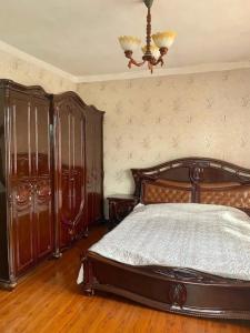 1 dormitorio con cama de madera y lámpara de araña en Room in the house, with mountain views and squirrels in the yard, en Almaty