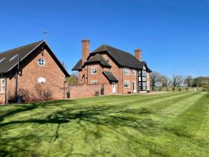 a large brick house with a large grass yard at Cheshire Retreat in Middlewich