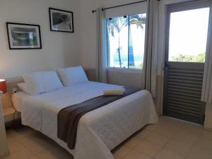 a bedroom with a large bed with a large window at Hotel Caieiras in Guaratuba