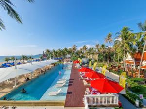 una piscina en un complejo con sombrillas y una playa en Beachfront Phuket en Bang Tao Beach