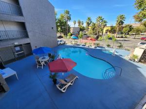 a large swimming pool with two umbrellas and chairs at Motel 6 Sacramento CA Natomas in Sacramento