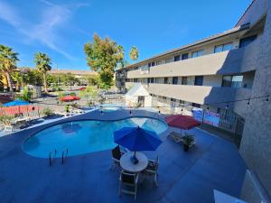 una piscina con sombrillas y sillas y un edificio en Motel 6 Sacramento CA Natomas en Sacramento