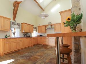 une grande cuisine avec des placards en bois et un vase avec un tournesol dans l'établissement Grains Barn Farm, à Burnley