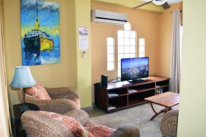 a living room with two chairs and a television at Beachfront Condo El Torreón San Juan del Sur in San Juan del Sur